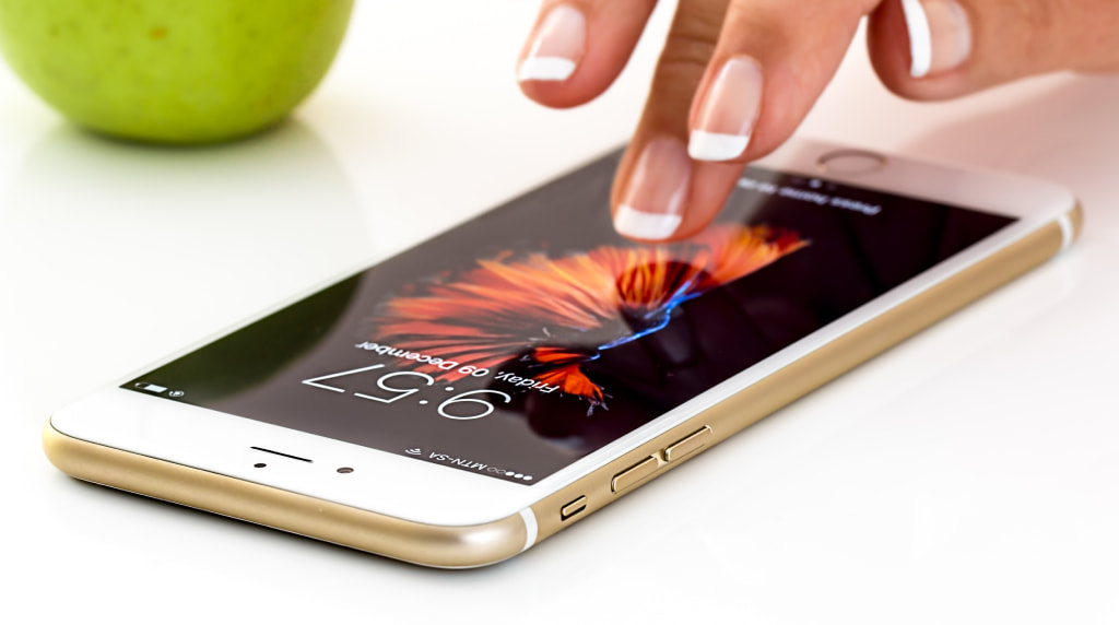 Mano usa smartphone con schermo acceso su tavolo bianco