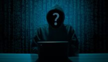 Figura incappucciata davanti al laptop tra codici digitali