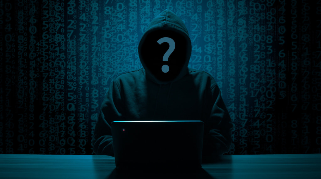 Figura incappucciata davanti al laptop tra codici digitali