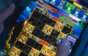Handen van iemand die een online gokkast speelt op een tablet