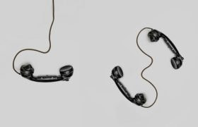 Drie oude zwarte telefoon-hoorns met snoer, op een grijze achtergrond