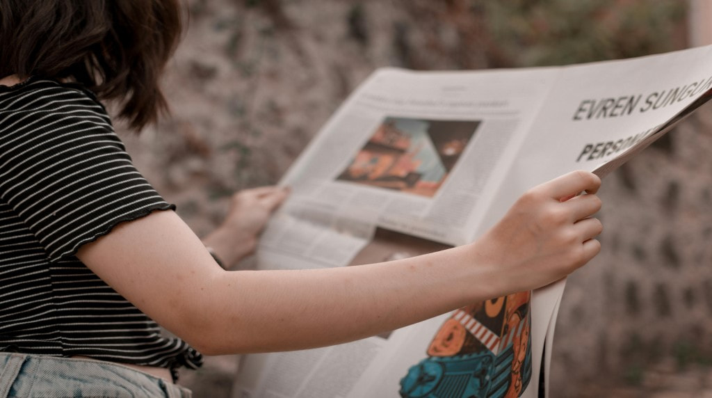 Vrouw leest een krant in de buitenlucht.