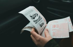 Iemand die in een auto meerdere jackpot-lotjes vasthoudt