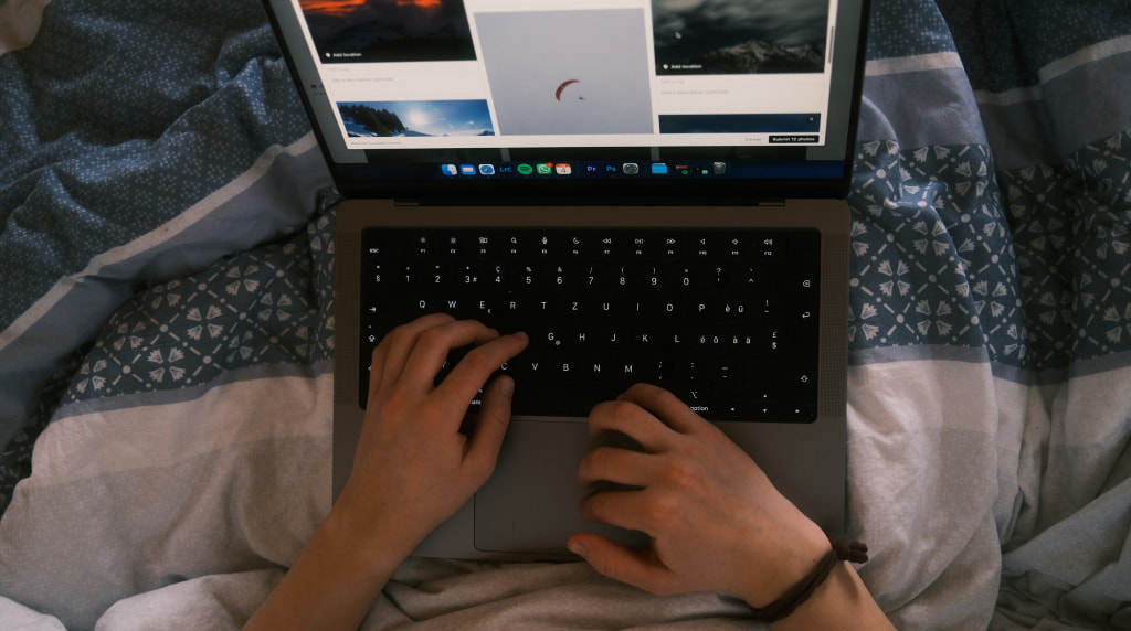 Twee kinderhanden die laptop vasthouden en parachutelanding bekijken vanuit bed.