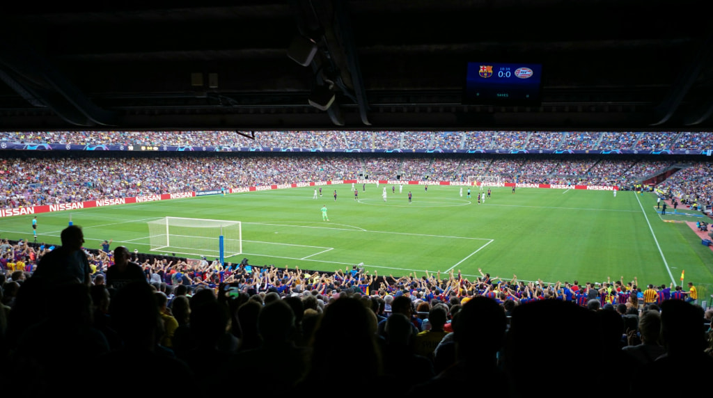 Zicht op een voetbalwedstrijd vanuit de tribune van een vol stadion