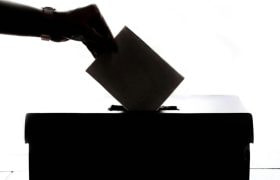 Foto met hoog contrast en hand die stembiljet in box stopt