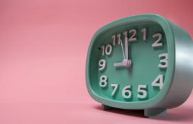 Mintgroene retro klok (wekker) op een roze achtergrond