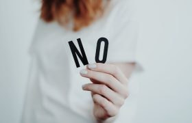 Vrouwenhand die de letters “N O” vasthoudt
