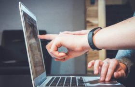 Handen die wijzen naar scherm van een laptop