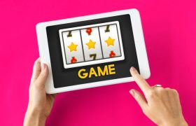 Vrouwenhanden met tablet, daarop staat een slot met het woordje “game”