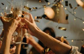 Handen die toosten op het nieuwe jaar met champagne en gouden glitters