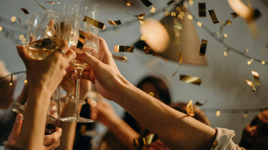 Handen die toosten op het nieuwe jaar met champagne en gouden glitters