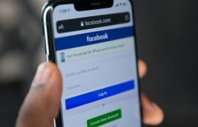 Hand met telefoon, daarop is het inlogscherm te zien van Facebook