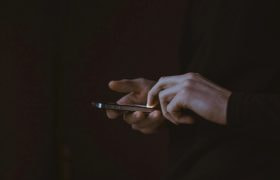 Handen die een smartphone vasthouden, donkere sfeer en achtergrond