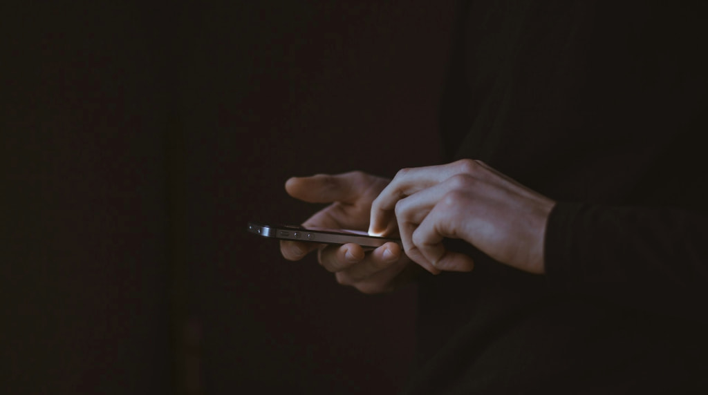 Handen die een smartphone vasthouden, donkere sfeer en achtergrond
