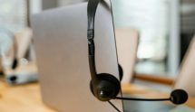 Achterkant van een laptop, waar een zwarte headset aan hangt