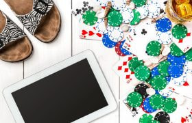 Niște papuci, o tabletă, chipsuri de poker și două pahare cu băuturi