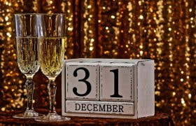 Două pahare de șampanie lângă un calendar cu 31 decembrie