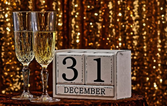 Două pahare de șampanie lângă un calendar cu 31 decembrie
