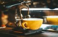 A close-up of an espresso machine pouring coffee into a yellow cup