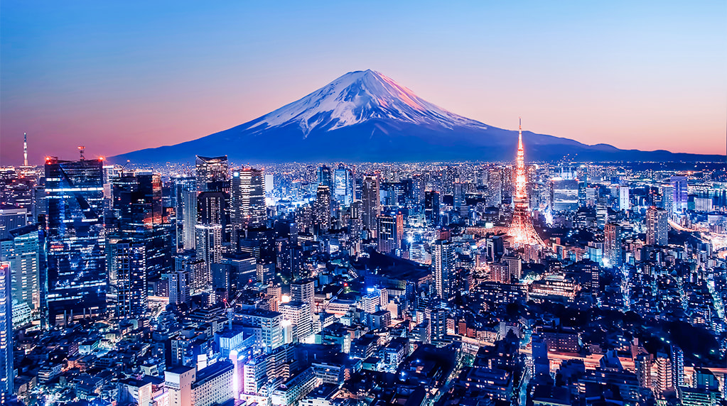 Tokyo skyline illuminated at dusk with Mount Fuji in the background and Tokyo Tower glowing among the city lights.