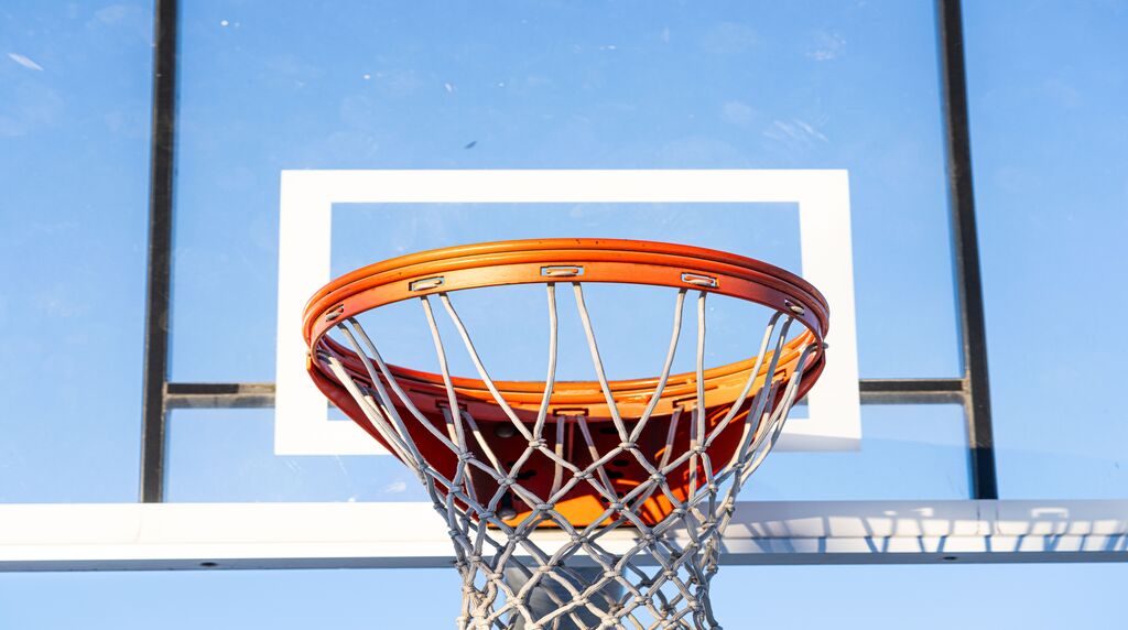 Close-up of an orange basketball hoop and net against a clear blue sky